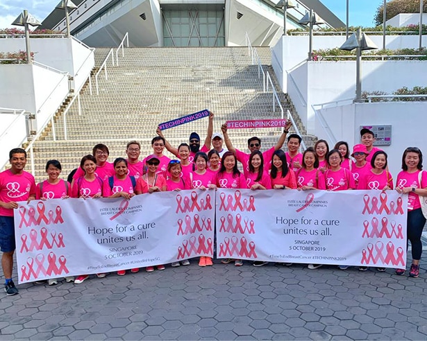 Group of people wearing pink holding breast cancer signs