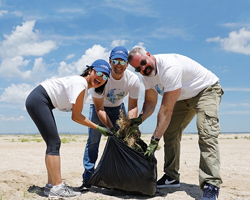 Three people on beach cleaning up