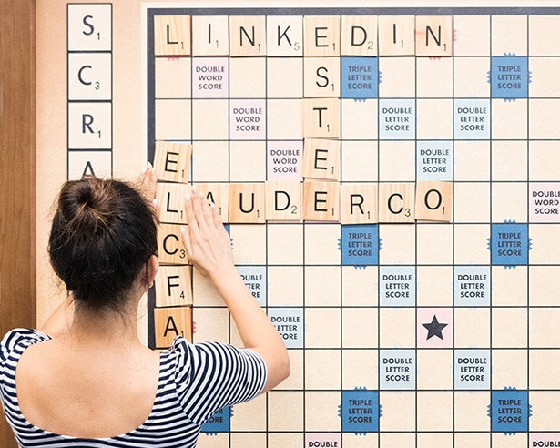 Person playing scrabble with words related to Estee Lauder