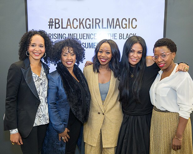 Five black women posing in front of a Black Girl Magic sign